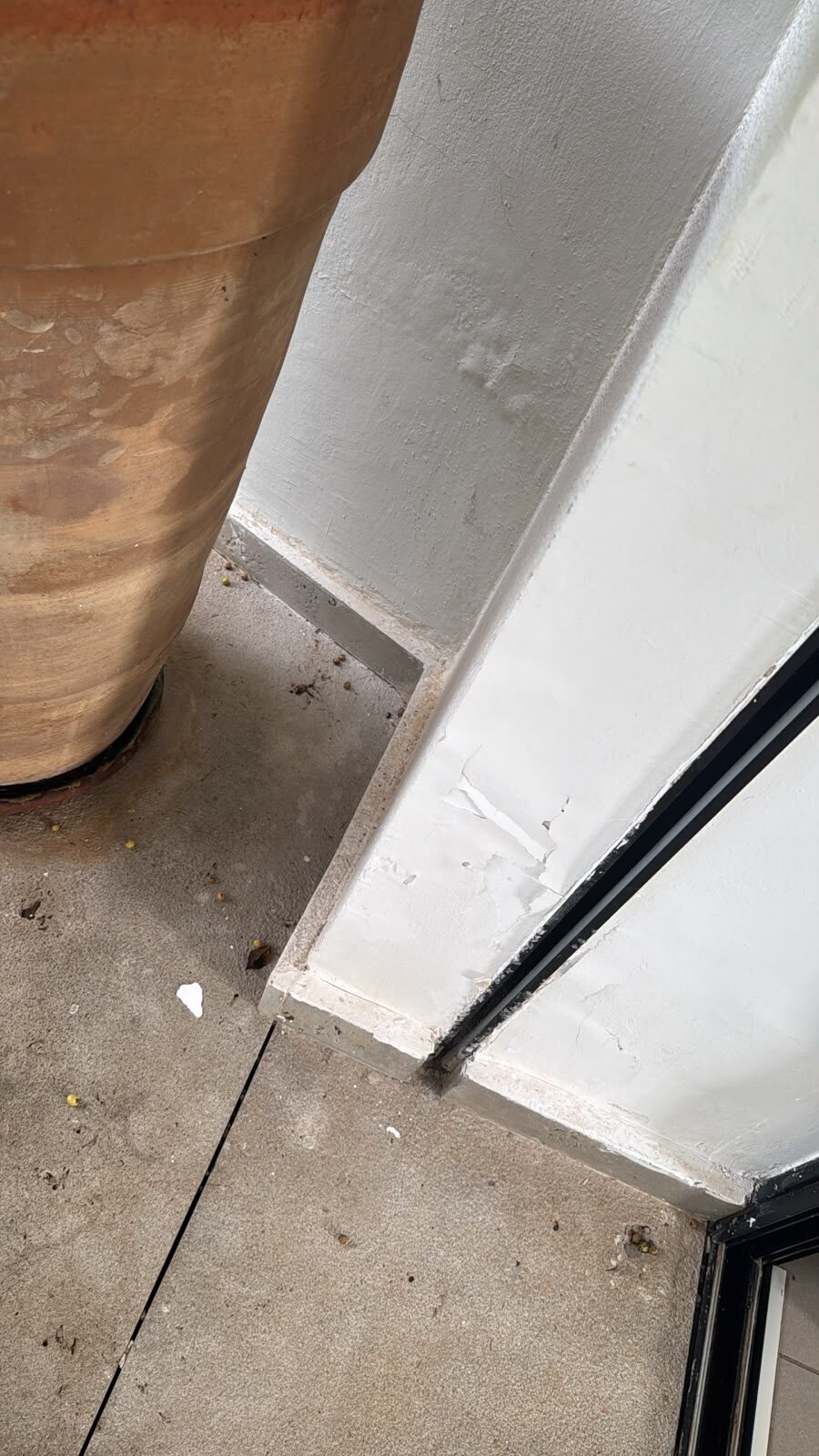 Peinture écaillée au pied d’un seuil extérieur sur terrasse